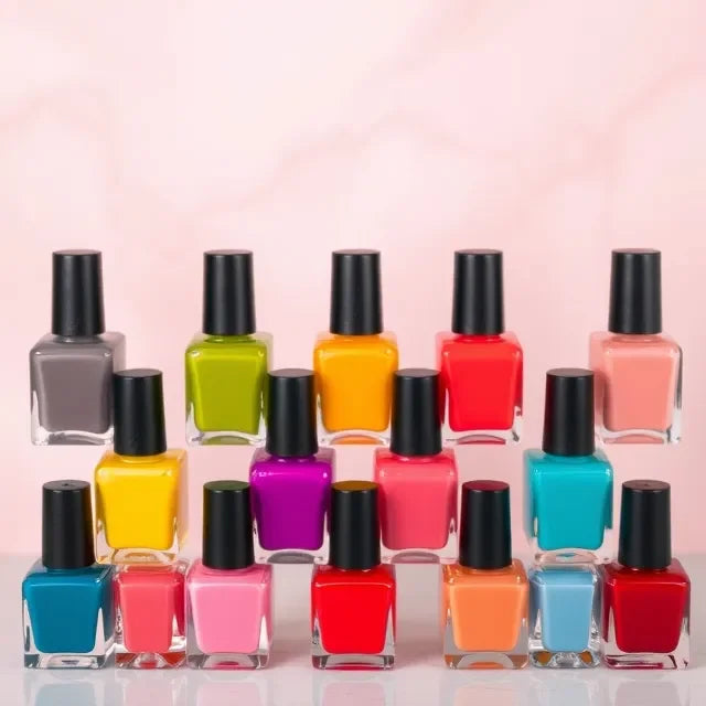 Row of colorful nail polish bottles with black caps on a light pink background