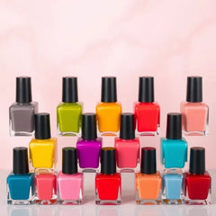 Row of colorful nail polish bottles with black caps on a light pink background