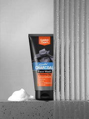 Tube of Golden Pearls Activated Charcoal Face Wash with a block of soap on a concrete surface.