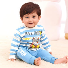Child wearing a blue and white striped outfit with a cartoon design, sitting on a soft surface.