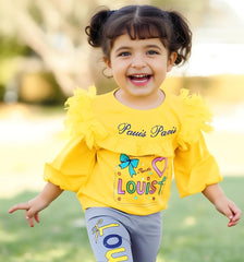 Child wearing a yellow outfit with colorful text and designs outdoors