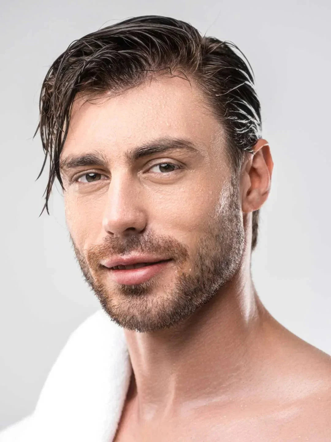 Man with styled hair and beard against a plain background