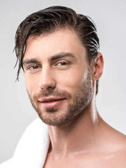 Man with styled hair and beard against a plain background
