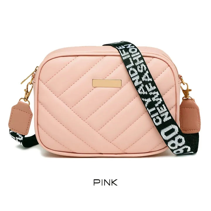 Pink quilted camera bag with a black and white strap on a white background