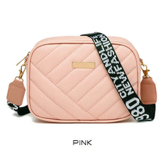 Pink quilted camera bag with a black and white strap on a white background